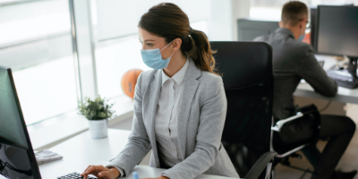 woman working at desk with PPE